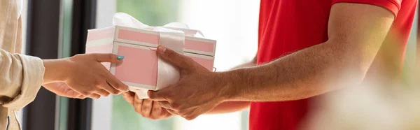 Tiro panorâmico de homem de entrega dando presente rosa à mulher — Fotografia de Stock