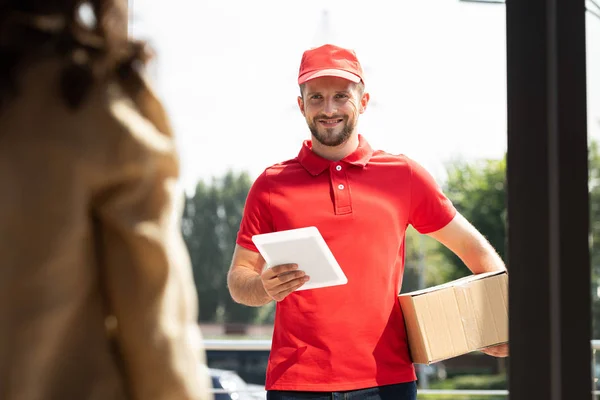 Foyer sélectif de livraison heureux homme tenant tablette numérique et boîte près de la femme — Photo de stock