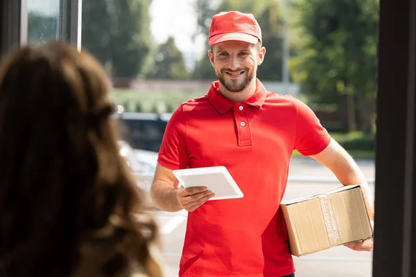 Selective focus of cheerful delivery man holding digital tablet and box near woman — Stock Photo