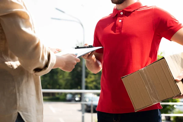 Recortado vista de entrega hombre dando portapapeles a la mujer - foto de stock