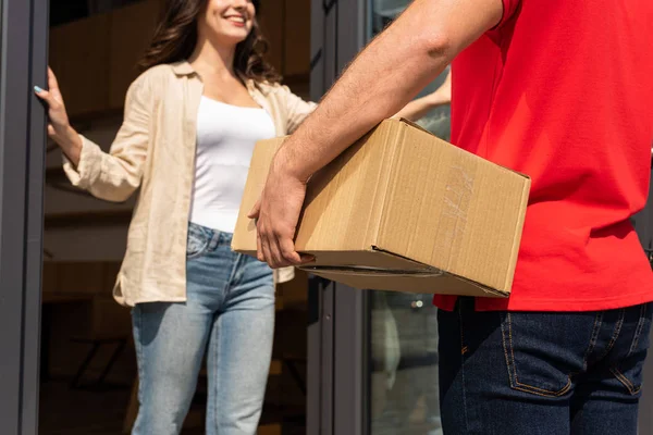 Selektiver Fokus von Liefermann, der Schachtel neben fröhlicher Frau hält — Stockfoto