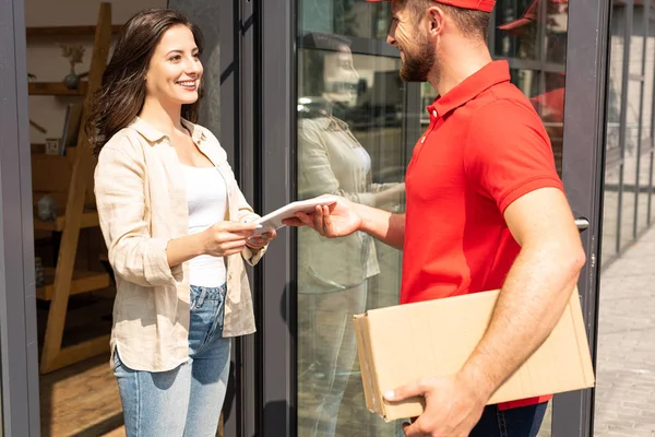 Bearded delivery man giving digital tablet to happy girl — Stock Photo