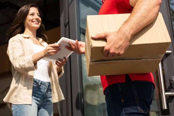 Low angle view of delivery man giving digital tablet to happy girl — Stock Photo