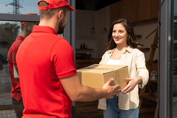 Entrega homem dando caixa de papelão para mulher feliz — Fotografia de Stock