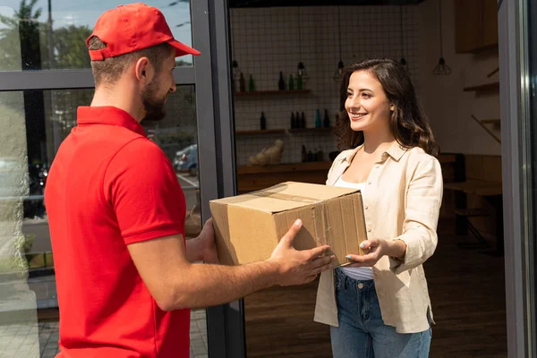 Barbudo entrega hombre dando caja de cartón a mujer alegre - foto de stock