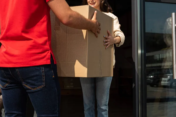 Vue recadrée de livraison homme donnant boîte de carton à fille — Photo de stock