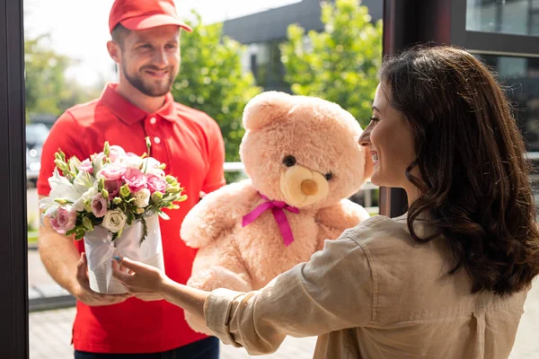 Enfoque selectivo de la mujer feliz recibir regalos de repartidor hombre - foto de stock