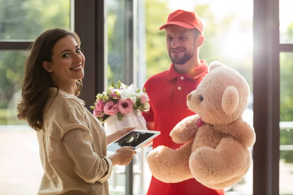 Femme heureuse tenant tablette numérique près de livraison homme avec des cadeaux — Photo de stock