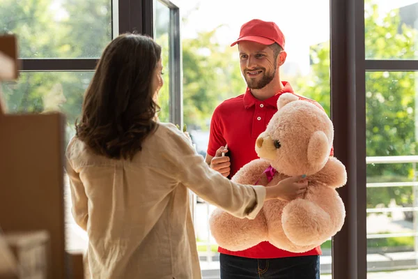 Selective focus of woman receiving teddy bear from delivery man — Stock Photo