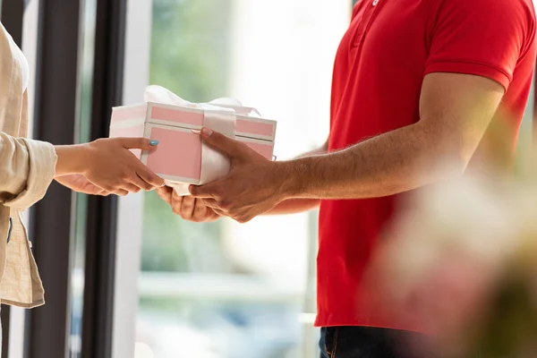 Cropped view of delivery man giving pink present to woman — Stock Photo