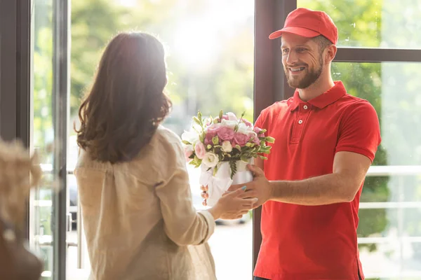 Selektiver Fokus des glücklichen Mannes mit Mütze, der der Frau Blumen schenkt — Stockfoto