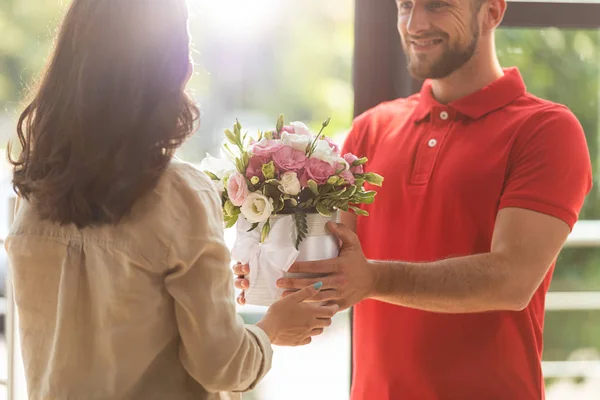 Vista ritagliata di felice consegna uomo dando fiori alla donna — Foto stock
