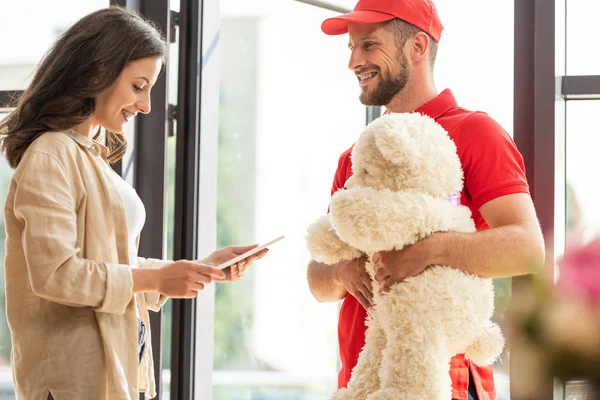 Attraktive Frau blickt auf digitales Tablet neben Mann mit Teddybär — Stockfoto