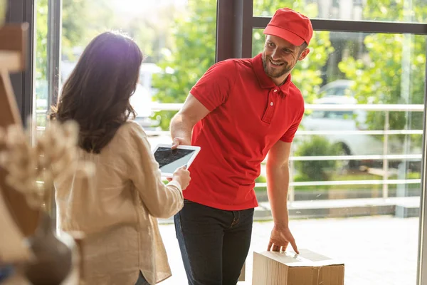 Foyer sélectif de livraison heureux homme regardant femme tenant tablette numérique avec écran blanc — Photo de stock