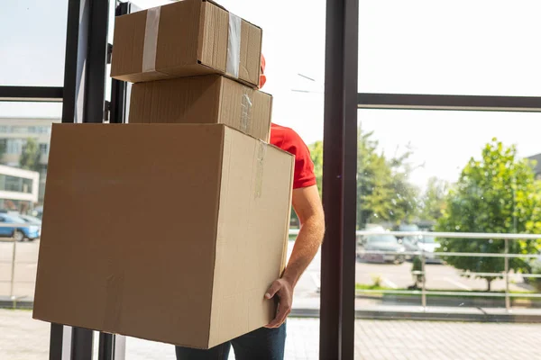 Hombre de entrega cubriendo la cara mientras sostiene cajas de cartón - foto de stock