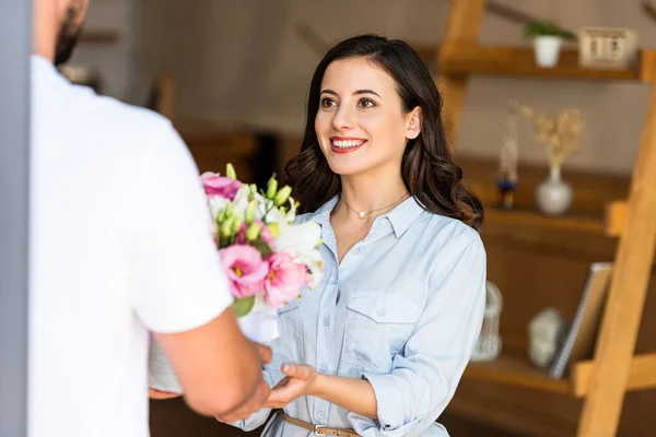 Vue recadrée de livraison homme donnant des fleurs à femme heureuse — Photo de stock