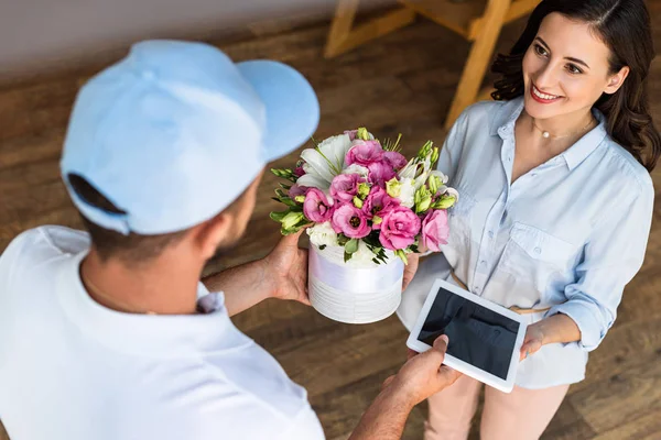 Visão aérea do homem de entrega dando flores e tablet digital com tela em branco para mulher alegre — Fotografia de Stock