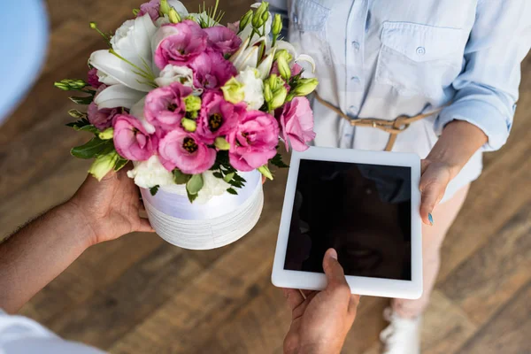 Вид зверху на чоловіка, що дарує квіти та цифровий планшет з порожнім екраном жінці — стокове фото