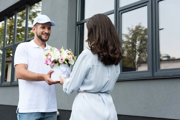 Heureux homme barbu en chapeau donnant des fleurs à la femme à l'extérieur — Photo de stock