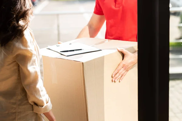 Vista cortada de homem de entrega segurando caixa perto da mulher — Fotografia de Stock