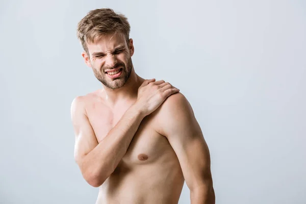 Hemdloser bärtiger Mann mit Schmerzen in der Schulter isoliert auf grau — Stockfoto