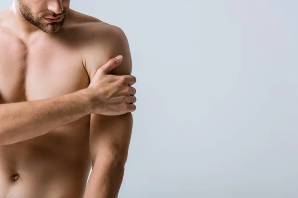 Teilbild eines hemdlosen, muskulösen Mannes mit Schmerzen im Arm isoliert auf grau — Stockfoto