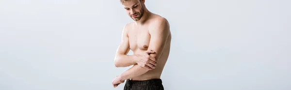 Panoramic shot of shirtless man with pain in elbow isolated on grey — Stock Photo