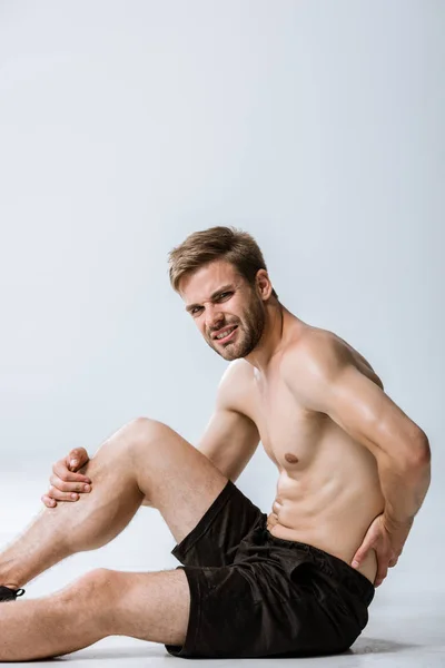 Shirtless bearded sportsman with lower back pain on grey — Stock Photo