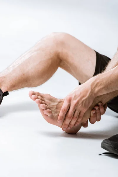 Partial view of sportsman with ankle pain on grey — Stock Photo