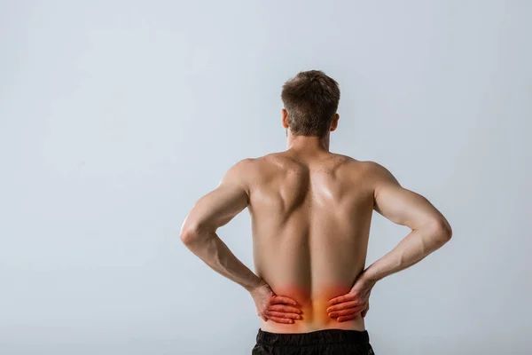 Back view of shirtless sportsman with lower back pain isolated on grey — Stock Photo