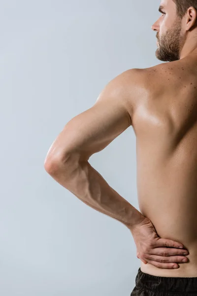 Cropped view of shirtless sportsman with lower back pain isolated on grey — Stock Photo