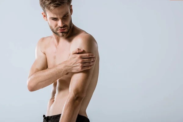 Sportif barbu torse nu avec douleur au bras isolé sur gris — Photo de stock