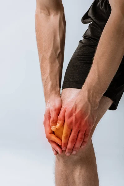 Обрізаний вид спортсмена з болем в коліні ізольований на сірому — стокове фото