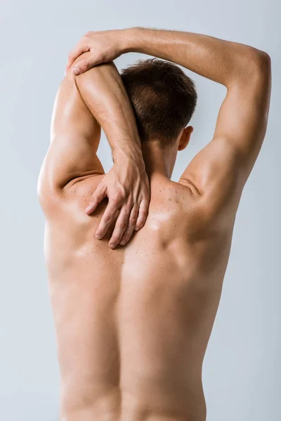 Back view of shirtless sportsman stretching isolated on grey — Stock Photo