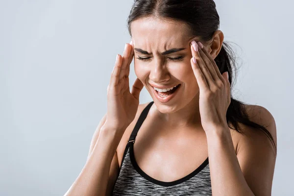 Jolie sportive avec maux de tête touchant tempes isolés sur gris — Photo de stock