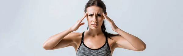 Panoramaaufnahme einer Sportlerin mit Kopfschmerzen, die Schläfen isoliert auf grau berührt — Stockfoto