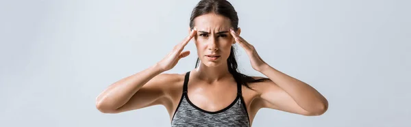 Plan panoramique d'une sportive avec des maux de tête touchant les tempes isolés sur du gris — Photo de stock