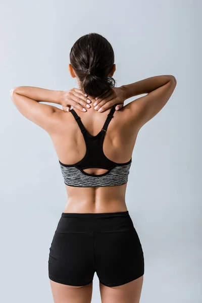 Back view of sportswoman with neck pain isolated on grey — Stock Photo