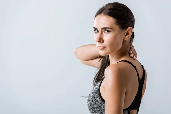 Attractive sportswoman with neck pain isolated on grey — Stock Photo