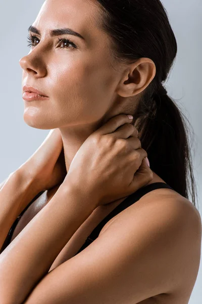 Attractive sportswoman with neck pain isolated on grey — Stock Photo