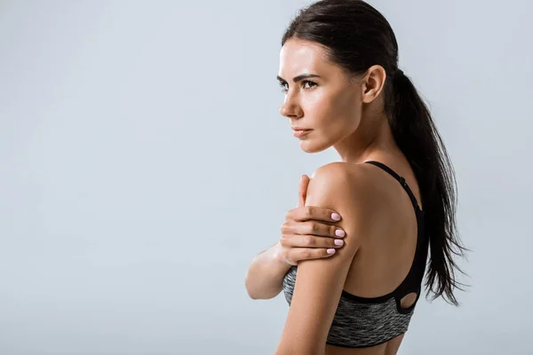 Attractive brunette sportswoman with arm pain isolated on grey — Stock Photo