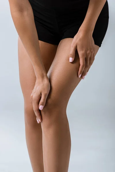 Vue recadrée d'une sportive avec douleur au genou isolée sur fond gris — Photo de stock