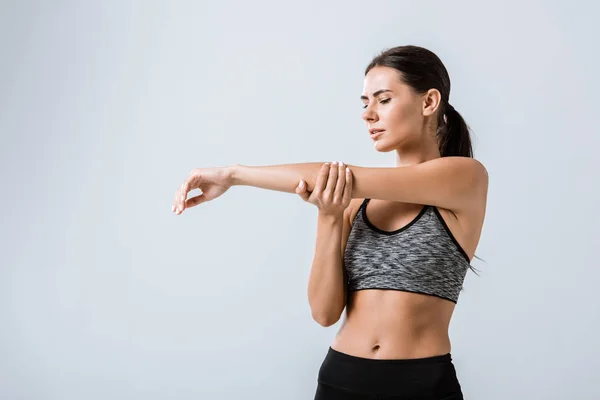 Attraktive Sportlerin mit Armschmerzen isoliert auf grau — Stockfoto