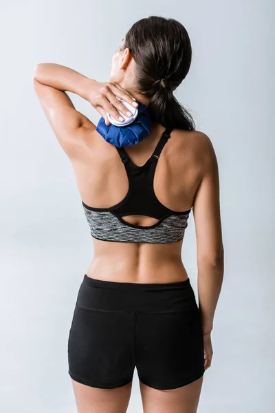 Vista posteriore di sportwoman utilizzando ghiaccio per il collo isolato su grigio — Foto stock