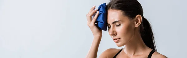 Panoramic shot of sportswoman with headache using ice isolated on grey — Stock Photo