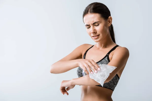 Leidende Sportlerin nutzt Eis für Ellbogen isoliert auf grau — Stockfoto