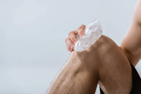 Частковий вид спортсмена з використанням льоду для коліна ізольовано на сірому — стокове фото