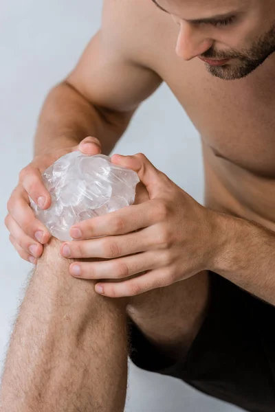 Visão parcial do desportista usando gelo para joelho isolado em cinza — Fotografia de Stock