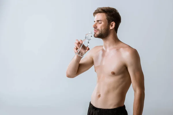 Hemdloser Sportler trinkt Wasser mit geschlossenen Augen isoliert auf grau — Stockfoto