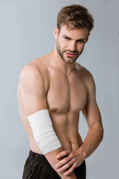 Hemdloser Sportler mit elastischem Verband am Ellbogen isoliert auf grau — Stockfoto